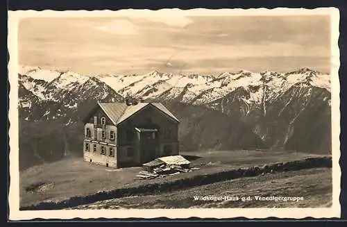 AK Wildkogel-Haus gegen die Venedigergruppe, Aussenansicht der Berghütte am Plateaurand mit Bergpanorama