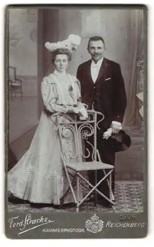 Fotografie Ferd. Stracke, Reichenberg, Elegantes Hochzeitspaar mit Stuhl im Atelier