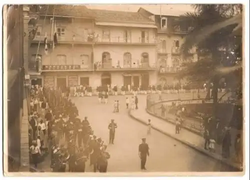 Fotografie unbekannter Fotograf, Ansicht Panama-Stadt, militärische Blaskapelle beim Umzug am Geschäft Ehrman & Co Banke