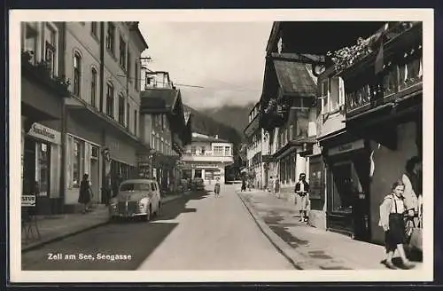 AK Zell am See, Seegasse mit Geschäften, Passanten und Oldtimern