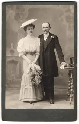 Fotografie Atelier Gebhardt, Marburg a. d. Drau, Brautpaar im Hochzeitskleid und im Anzug mit Brautstrauss