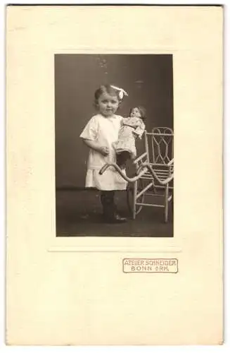 Fotografie Atelier Schneider, Bonn a. Rh., niedliches kleines Mädchen Elli Rühenbeck mit ihrer Puppe und Puppenwagen