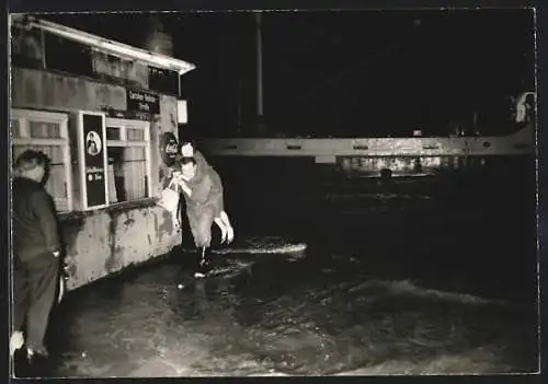 Foto-AK Hamburg, Mann trägt Dame durchs Wasser, Sturmflut 1962