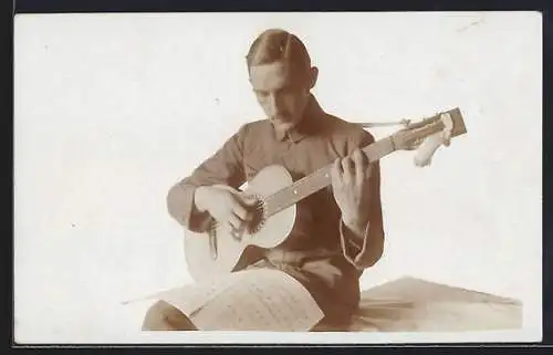 Foto-AK Herr spielt mit Noten auf dem Schoss Gitarre