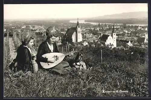 AK Krems a.d. Donau, zwei Frauen in Tracht mit Laute auf dem Weinberg mit Blick auf den Ort