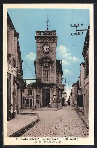 AK Saintes-Maries-de-la-Mer, Rue de l`Hôtel-de-Ville avec horloge et bâtiments environnants