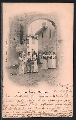 AK Maillanne, Une rue animée avec des femmes en costume traditionnel sous un arc en pierre