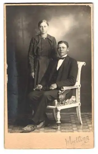 Fotografie Herm. Westling, Sala, Stehende Frau und sitzender Mann in eleganter Garderobe