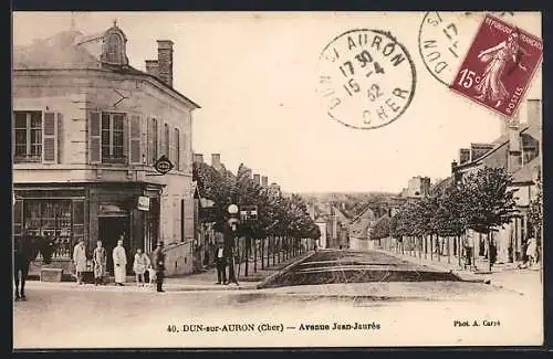 AK Dun-sur-Auron, Avenue Jean-Jaurès animée avec passants et bâtiments historiques