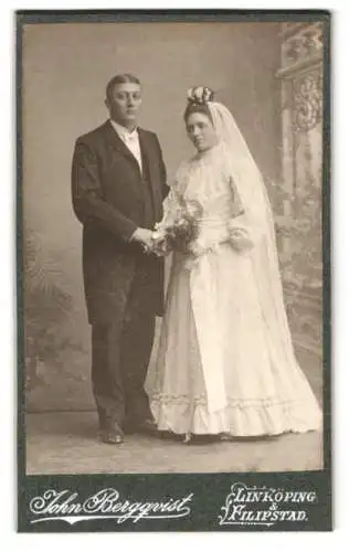 Fotografie John Bergquist, Linköping, Ehepaar im Brautkleid und Anzug mit Brautstrauss