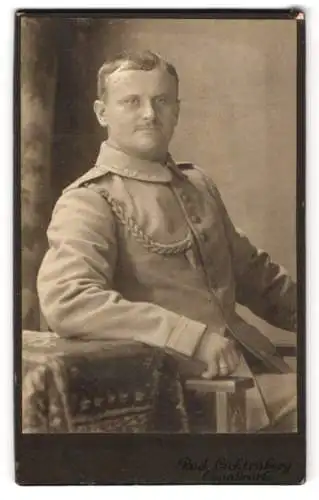 Fotografie Rud. Lichtenberg, Osnabrück, Möserstrasse 24, Soldat in Uniform mit Schützenschnur, sitzend