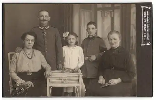 Fotografie M. Weiland, Berlin, Uffz. in Uniform nebst Familie, Sohn in Uniform mit Trauerflor, Kriegsausmarsch