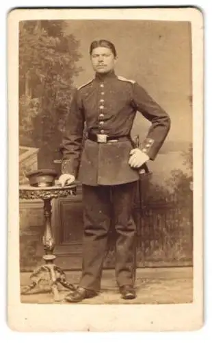 Fotografie C. Degèle, Hameln, Emmernstr. 11, Soldat in Uniform mit Bajonett vor einer Studiokulisse