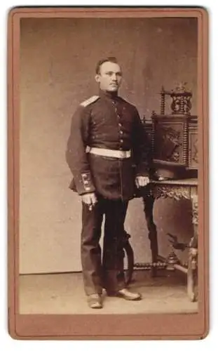 Fotografie F. Pfeiffer, Celle, Westcellertor 15, Soldat in Uniform neben kunstvoll verziertem Tisch