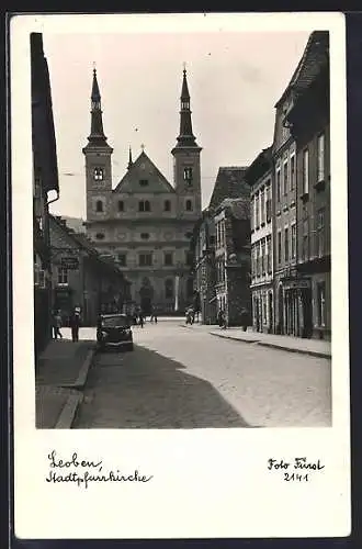 AK Loeben, Stadtpfarrkirche mit Vorplatz, Auto und Geschäfte