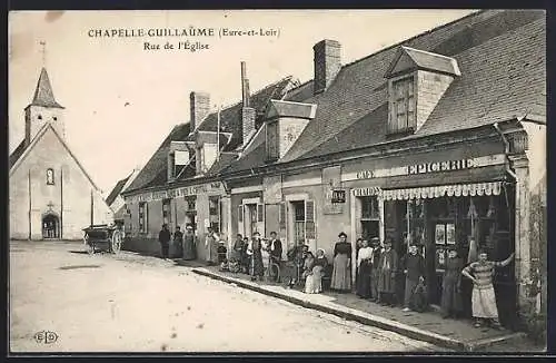 AK Chapelle-Guillaume, Rue de l`Église avec des habitants devant les commerces et l`église à l`arrière-plan