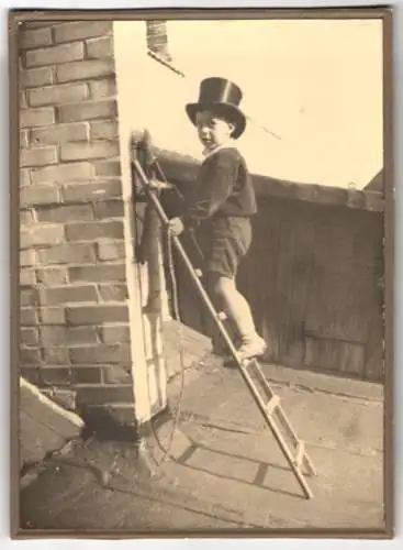 Fotografie unbekannter Fotograf, Ansicht Goldberg i. M., Knabe als Schornsteinfeger auf Leiter am Schornstein, 1933