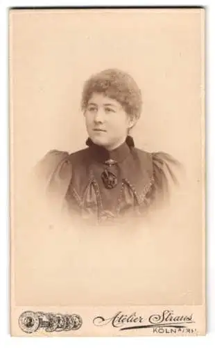 Fotografie Atelier Straus, Köln a. Rh., junge Dame im dunklen Kleid mit Brosche und Locken