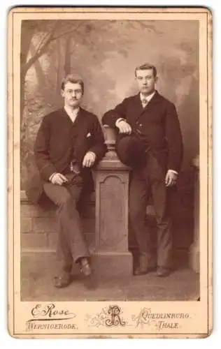 Fotografie E. Rose, Wernigerode, zwei junge Herren in Anzügen mit Melone vor einer Studiokulisse