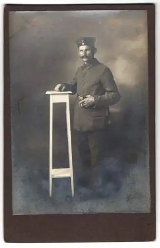 Fotografie unbekannter Fotograf und Ort, Soldat Rgt. 110 in Uniform mit Krätzchen nebst Podest