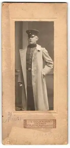 Fotografie E. Volkmann, Colmar, Kopfhausstr. 6, Soldat in Uniform mit Mantel & Schirmmütze