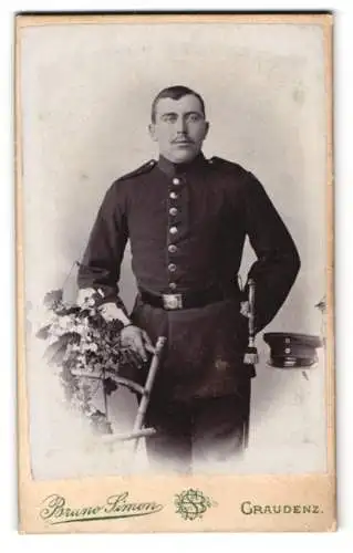 Fotografie Bruno Simon, Graudenz, Lindenstr. 38, Soldat in Uniform mit Mütze Bajonett und Blumenarrangement