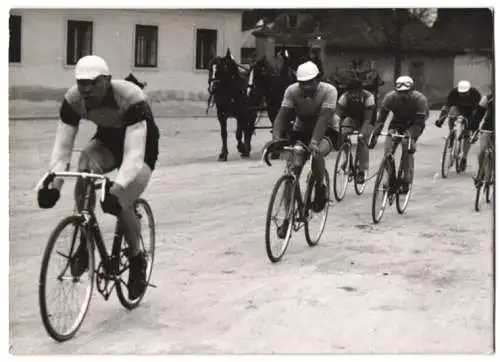 Fotografie Dainko, Fahrrad-Rennen Wien - Eisenstadt - Wien 1940, Radrennfahrer passieren ein Dorf