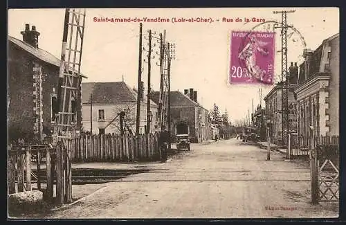 AK Saint-Amand-de-Vendôme, Rue de la Gare avec passage à niveau et bâtiments adjacents