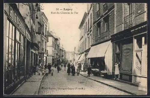 AK Lagny, Rue du Chemin de Fer animée avec passants et boutiques