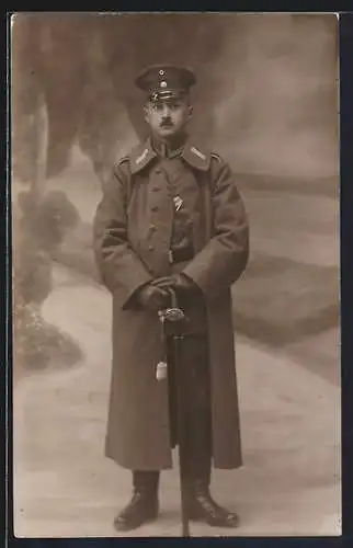 Foto-AK Soldat im Uniformmantel mit Schirmmütze, Uniformfoto