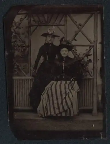 Fotografie Ferrotypie zwei hübsche junge Damen in dunklen Kleidern vor einer Studiokulisse