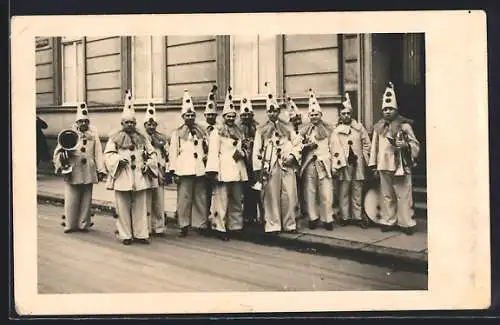 Foto-AK Harlekingruppe mit Blechblasinstrumenten auf der Strasse vor einem Gebäude