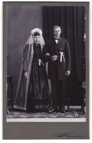 Fotografie L. Seebeck, Bremervörde, junges Brautpaar im schwarzen Hochzeitskleid und im Anzug mit Schleife