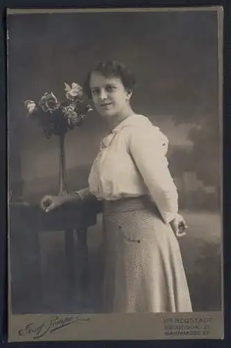 Fotografie Josef Pompe, Wr. Neustadt, Brodtischgasse 21, Frau in heller Bluse neben Blumenarrangement