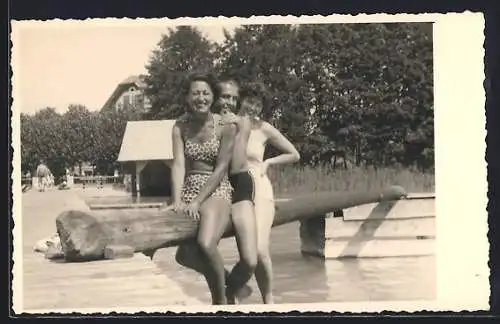 Foto-AK Pörtschach, Fröhliches Trio in Badeanzug und Badehose an einem Steg am Wasser, 1957