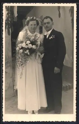 Foto-AK Braut im weissen Kleid mit Bouquet neben ihrem Bräutigam im Anzug, Hochzeit