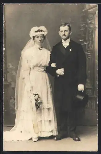 Foto-AK Braut im weissen Kleid mit Bouquet neben ihrem Bräutigam im Anzug mit Zylinder, Hochzeit