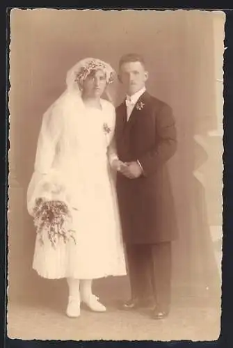 Foto-AK Braut im weissen Kleid mit Bouquet neben ihrem Bräutigam im Anzug mit Ansteckblume, Hochzeit