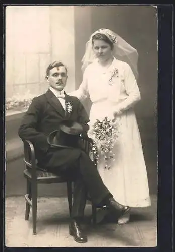 Foto-AK Braut im weissen Kleid mit Bouquet neben ihrem sitzenden Bräutigam Lukas im Anzug, Hochzeit