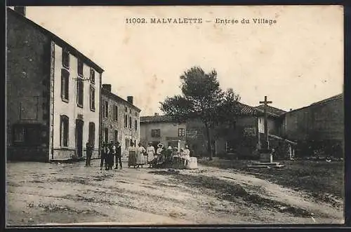 AK Malvalette, Entrée du Village avec des habitants rassemblés près d`une croix en pierre