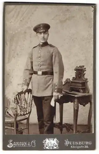 Fotografie Samson & Co, Duisburg, Königstr. 38, Soldat in Uniform neben Tisch mit Dekoration