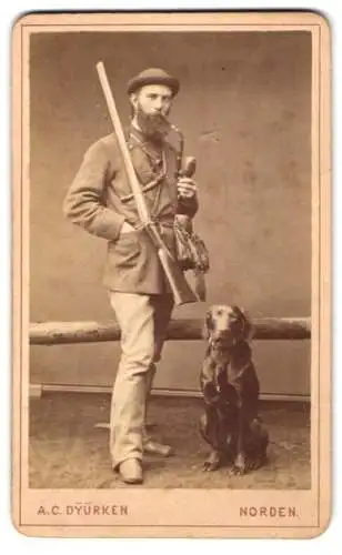 Fotografie A. C. Dyürken, Norden, ostfriesischer Jäger mit seinem Jagdhund und Flinte raucht Pfeife