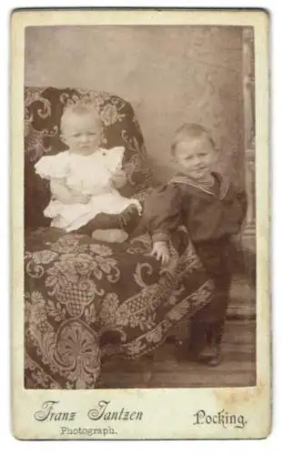 Fotografie Franz Jantzen, Pocking, Zwei kleine Kinder auf dekorativem Sessel