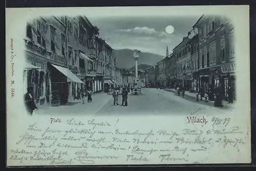 Mondschein-AK Villach, Platz mit Geschäften und Denkmal