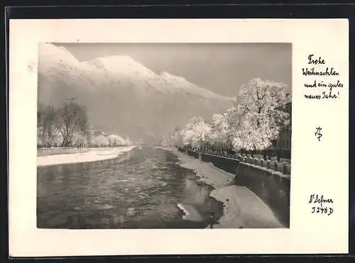 Foto-AK Adalbert Defner: Winterlich verschneite Ortschaft am Fluss, Festtagsgrüsse