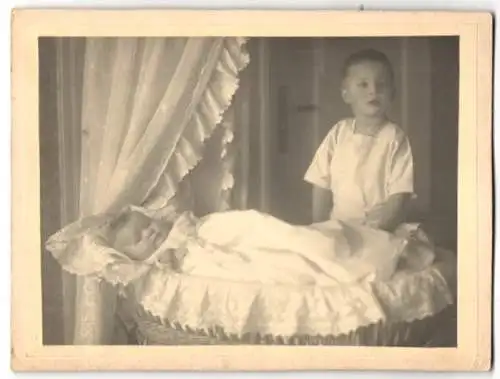 Fotografie unbekannter Fotograf und Ort, Knabe Hans Otto mit seiner Schwester Ruth Hüppe im Kinderbett