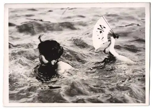 Fotografie Japanische Schwimmerin hält mit akrobatischer Leistung ihren Fächer selbst im Wasser