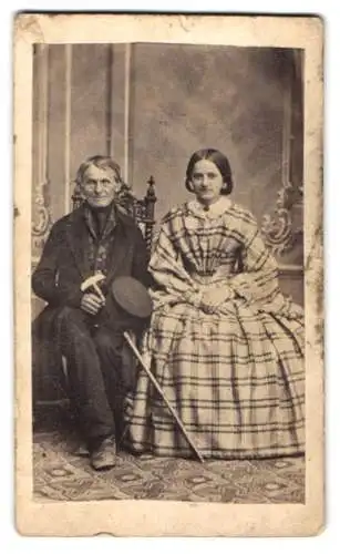 Fotografie Aug. Roehler, Reichenbach i. Schl., Sitzender Herr mit Dame im karierten Kleid