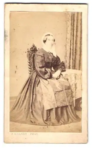 Fotografie F. Brandt, Flensburg, Frau in elegantem Kleid sitzt an einem Tisch