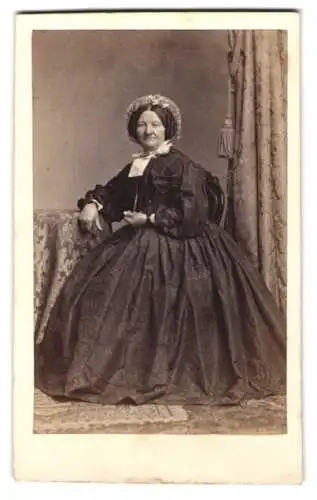 Fotografie A. Siegmund, Hamburg, Ältere Dame in voluminösem Kleid mit Buch